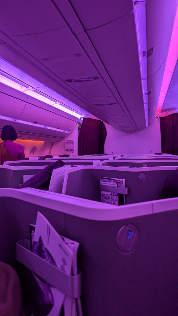 Interior view of Thai Airways Boeing 787-9 business class cabin with purple mood lighting and seating arrangements.